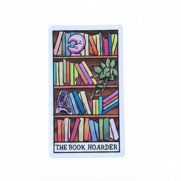 Card titled 'The Book Hoarder' held by a hand on a white fluffy surface with wooden background