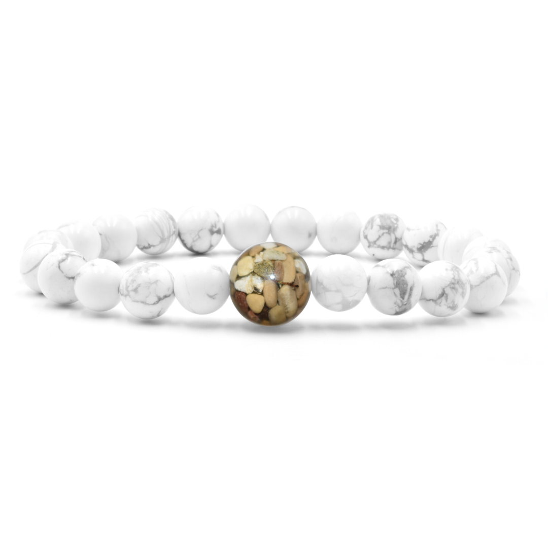 Stretch bracelet made of round white howlite beads sits on a white background. The center bead is larger and with irregularly shaped areas in shades of brown and tan