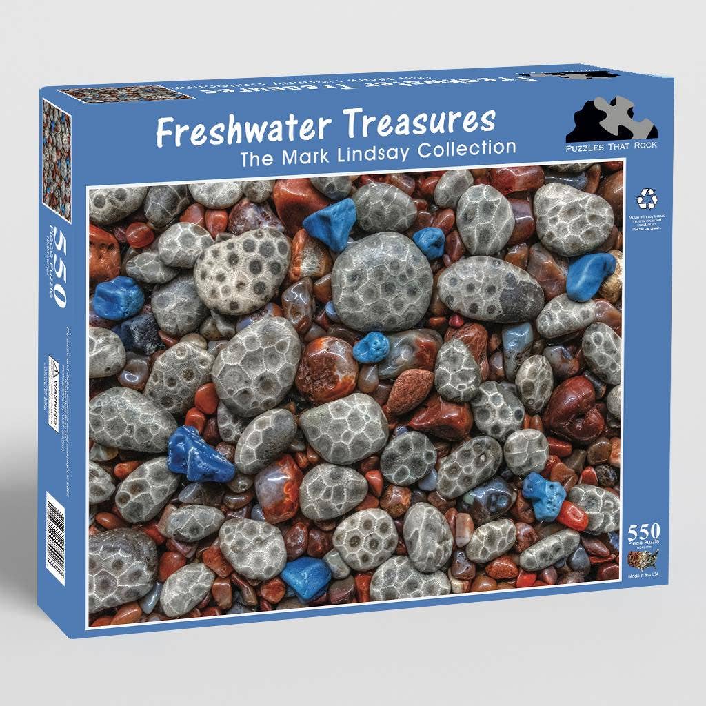 Jigsaw puzzle box featuring a Petoskey stones, Leland Blue, and Agates. The blue box says 'Freshwater Treasures' and 'The Mark Lindsay Collection' in text.