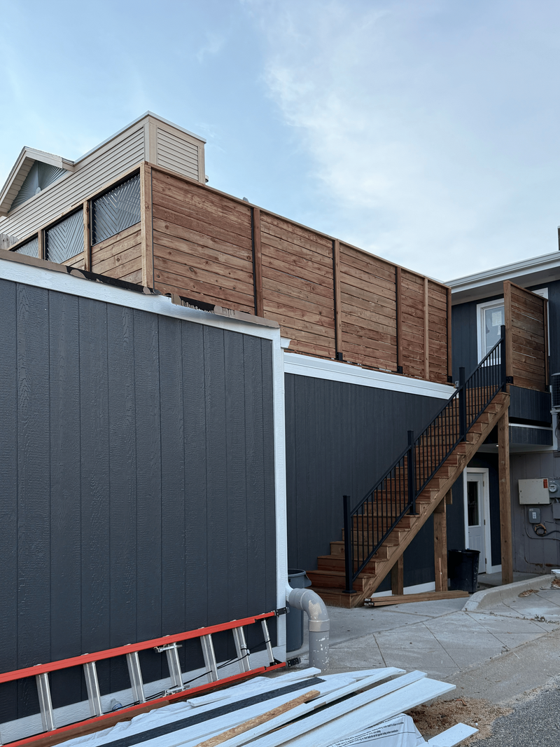 An outdoor staircase with wooden railings and a black metal frame.