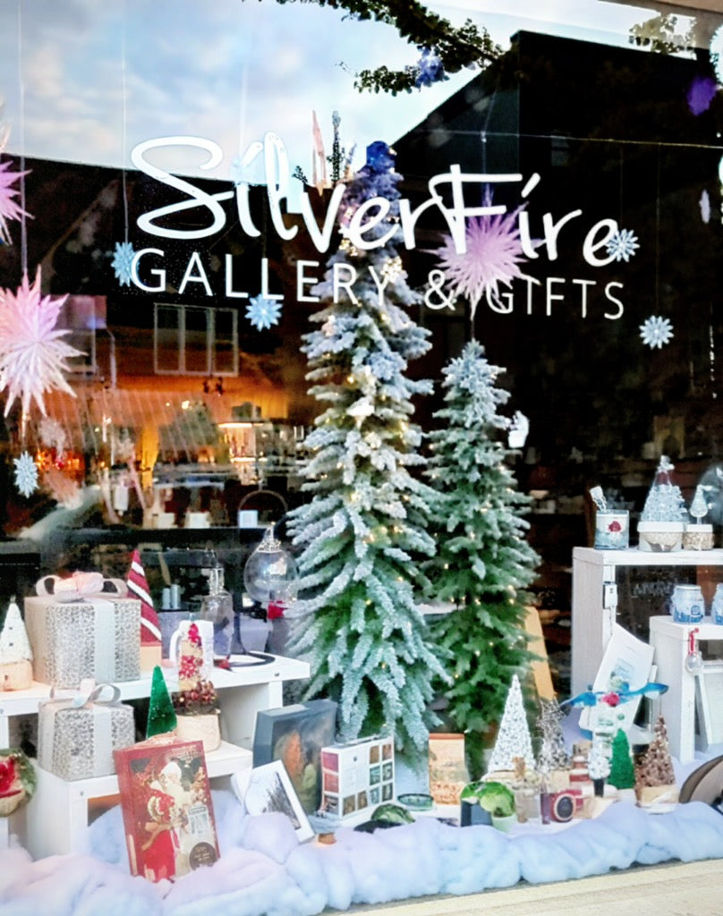 Display of Christmas-themed items in a store window with 'Silver Fire Gallery & Gifts' sign.