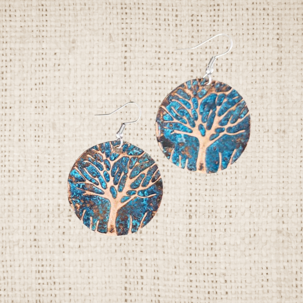 Pair of circle earrings with tree design on a textured beige background