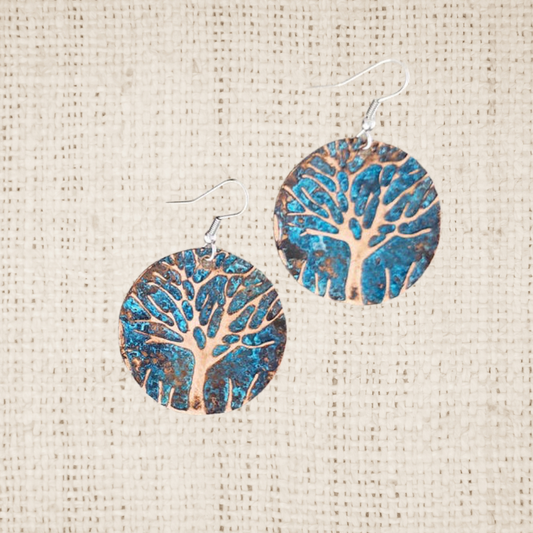 Pair of circle earrings with tree design on a textured beige background