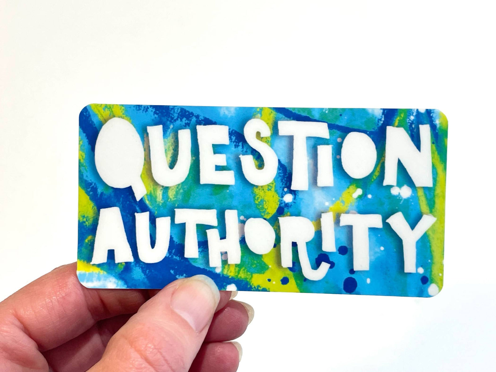 Bright blue and green sticker with 'QUESTION AUTHORITY' white text held by a hand against a white background
