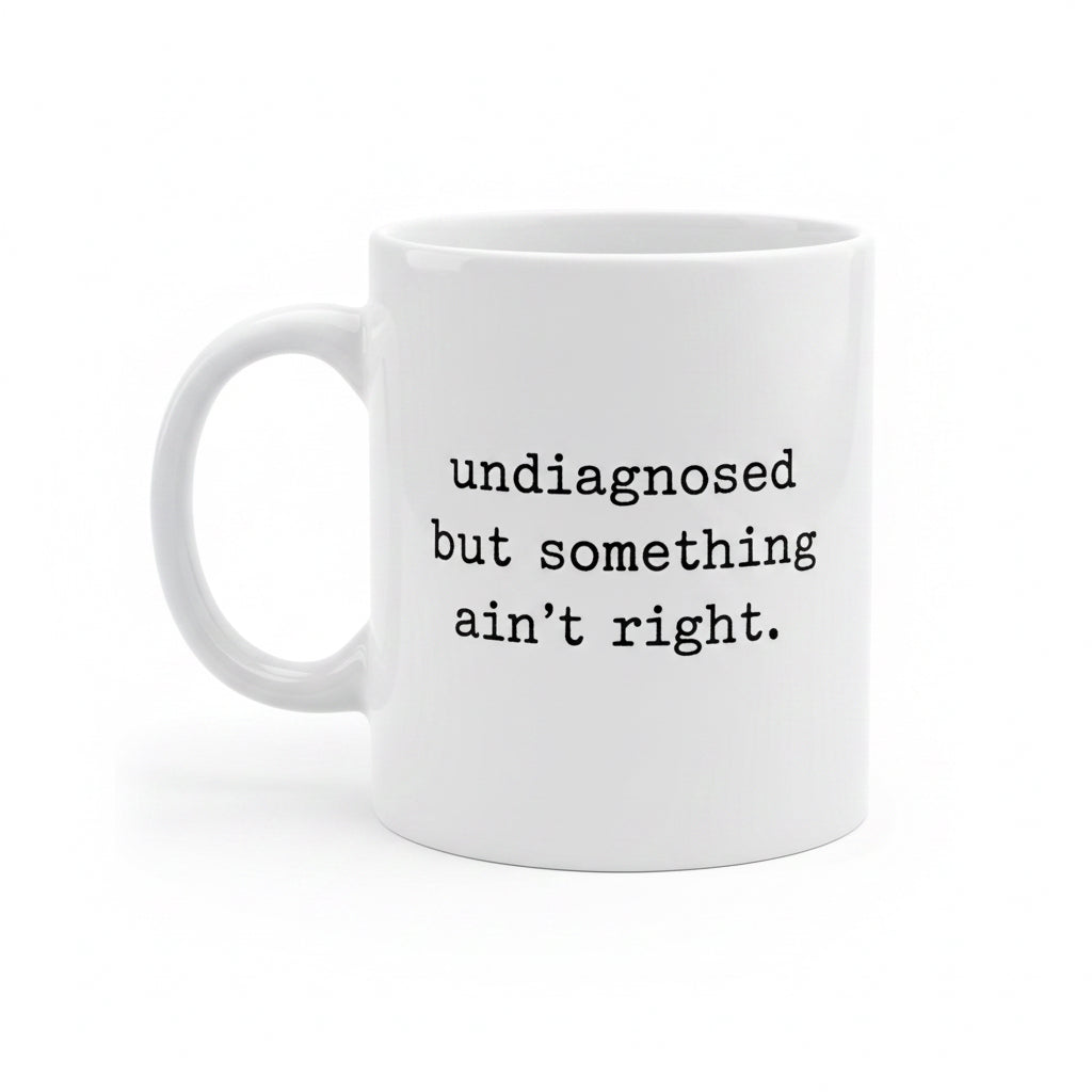 White mug with text 'undiagnosed but something ain't right' on a white background
