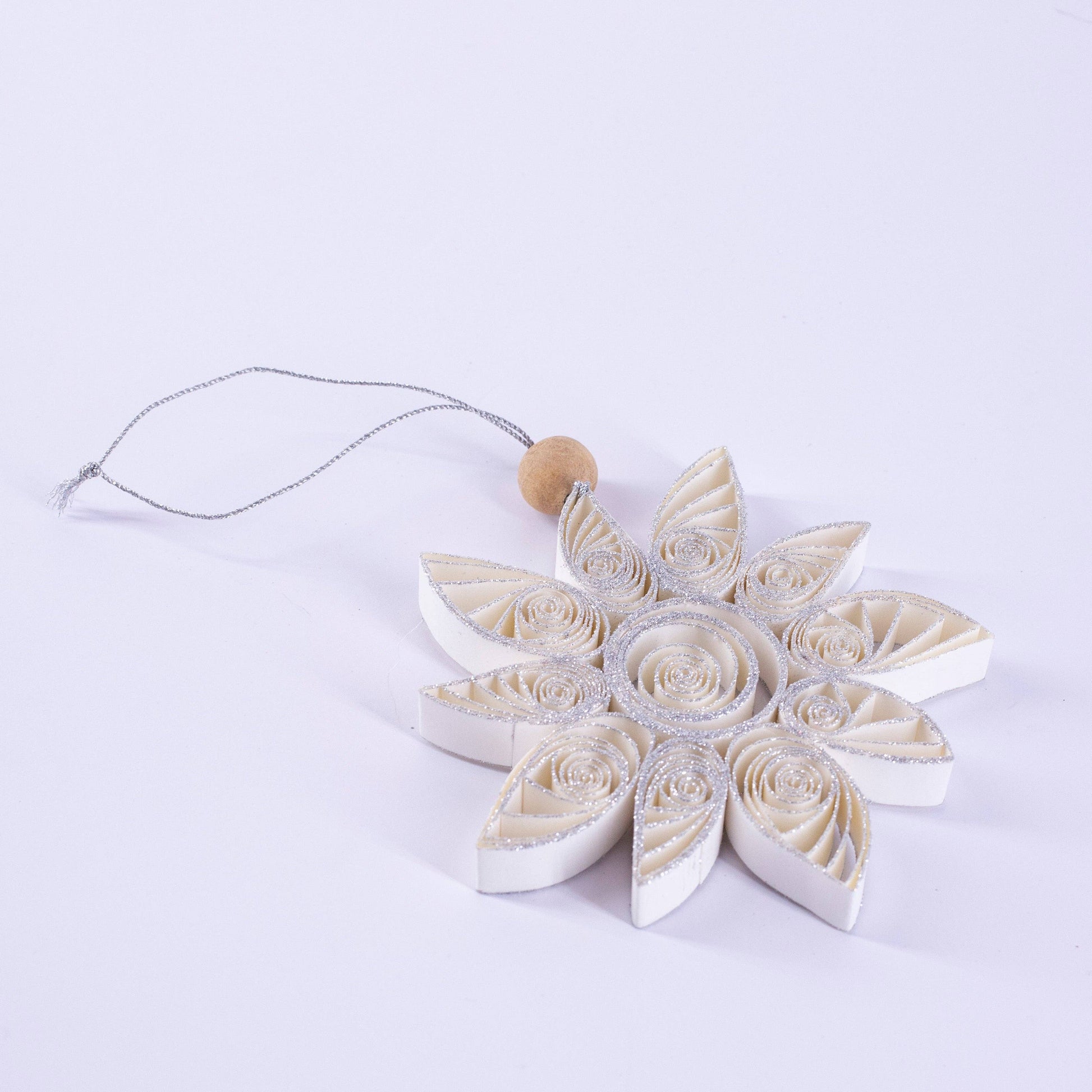 Decorative snowflake ornament with a wooden bead on a white background