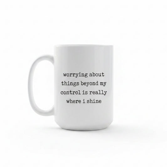 White mug with black text 'worrying about things beyond my control is really where i shine' in a kitchen on a wooden table.
