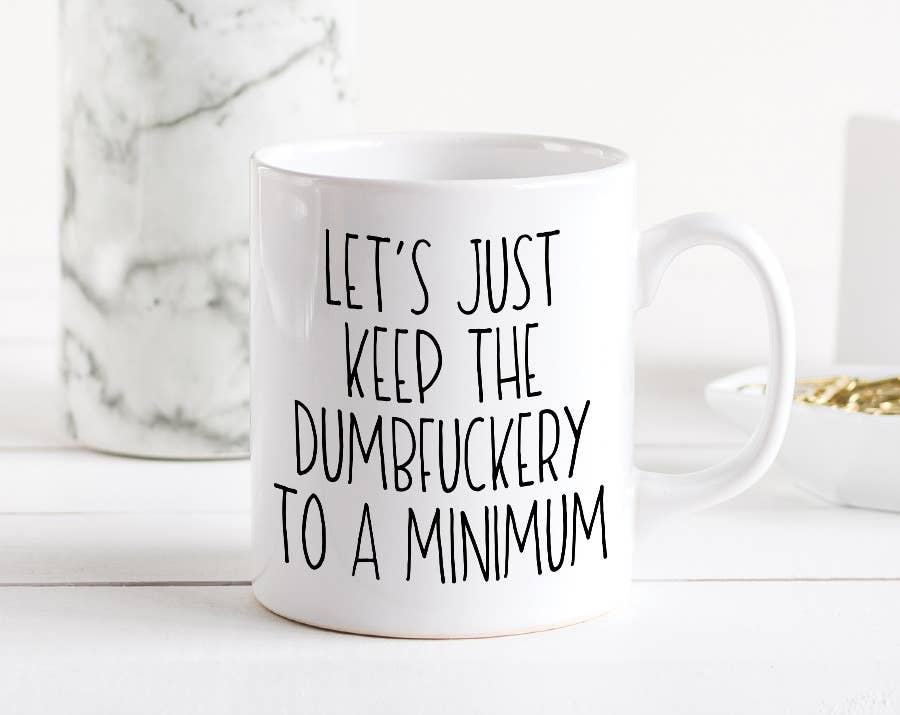 A white coffee mug with black text that looks handwritten in capital letters. The quote on the mug reads &quot;Let&#39;s just keep the dumbfuckery to a minimum&quot;