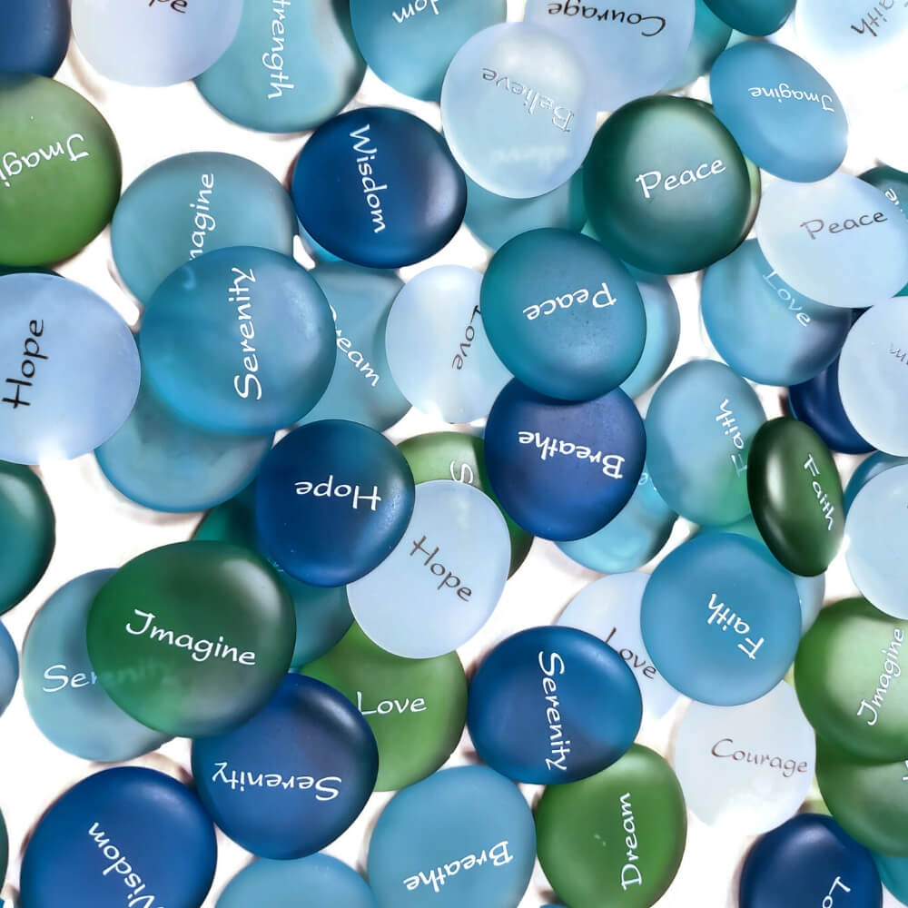 Smooth blue, teal, green, light blue and white glass "stones" with a word written on each in white. Words include Serenity, Hope, Imagine, Wisdom, Peace, Breathe, Faith, Dream, and Love.