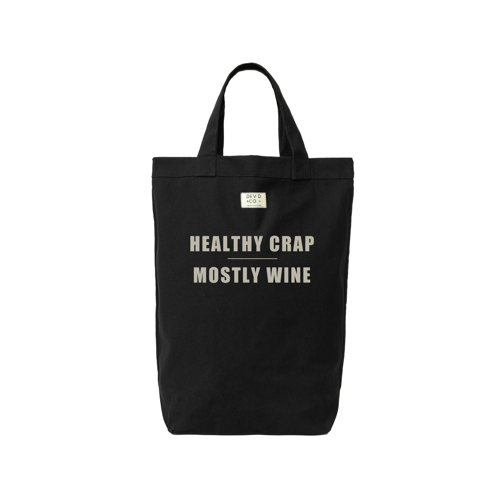 Tall rectangular shaped black canvas bag stands on a white background. Centered all capitals quote reads Healthy Crap Mostly Wine.
