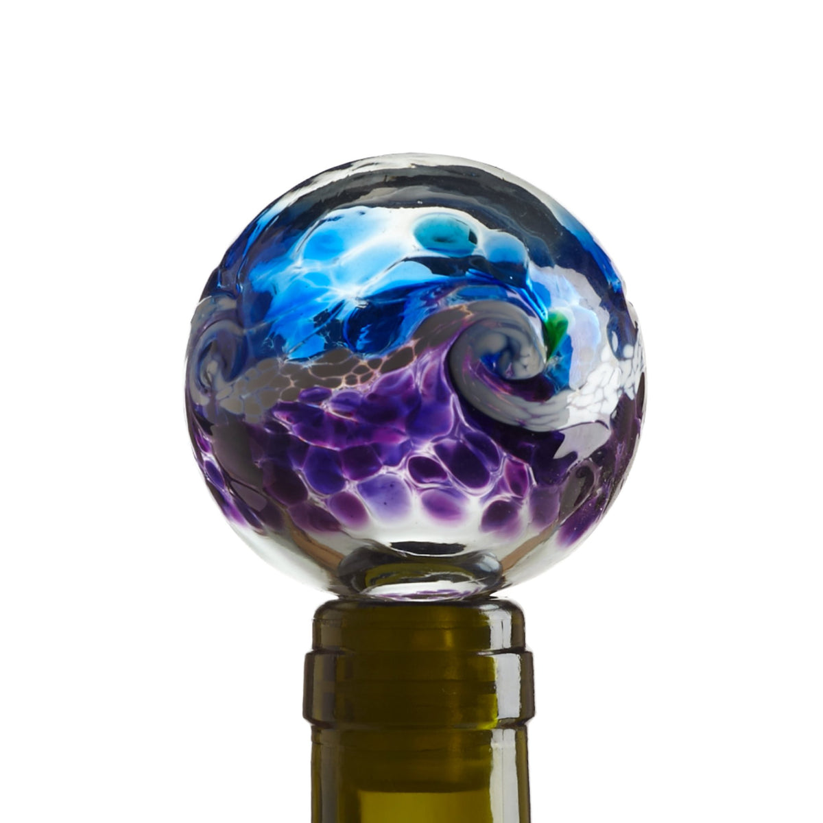 Blown glass globe wine stopper with spatterings of transparent blue on the top half and transparent purple on the bottom. The two colors meet in a swirl of white and gray that looks like a wave. Pictured in the neck of a green wine bottle.